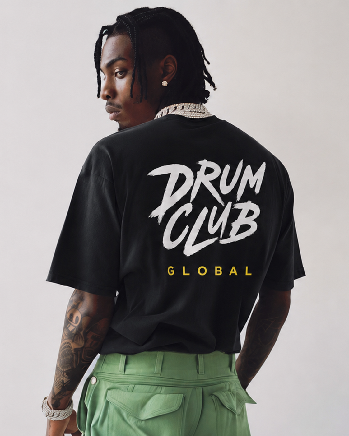 Person wearing a black t-shirt with 'Drum Club Global' text on the back, standing against a plain background.