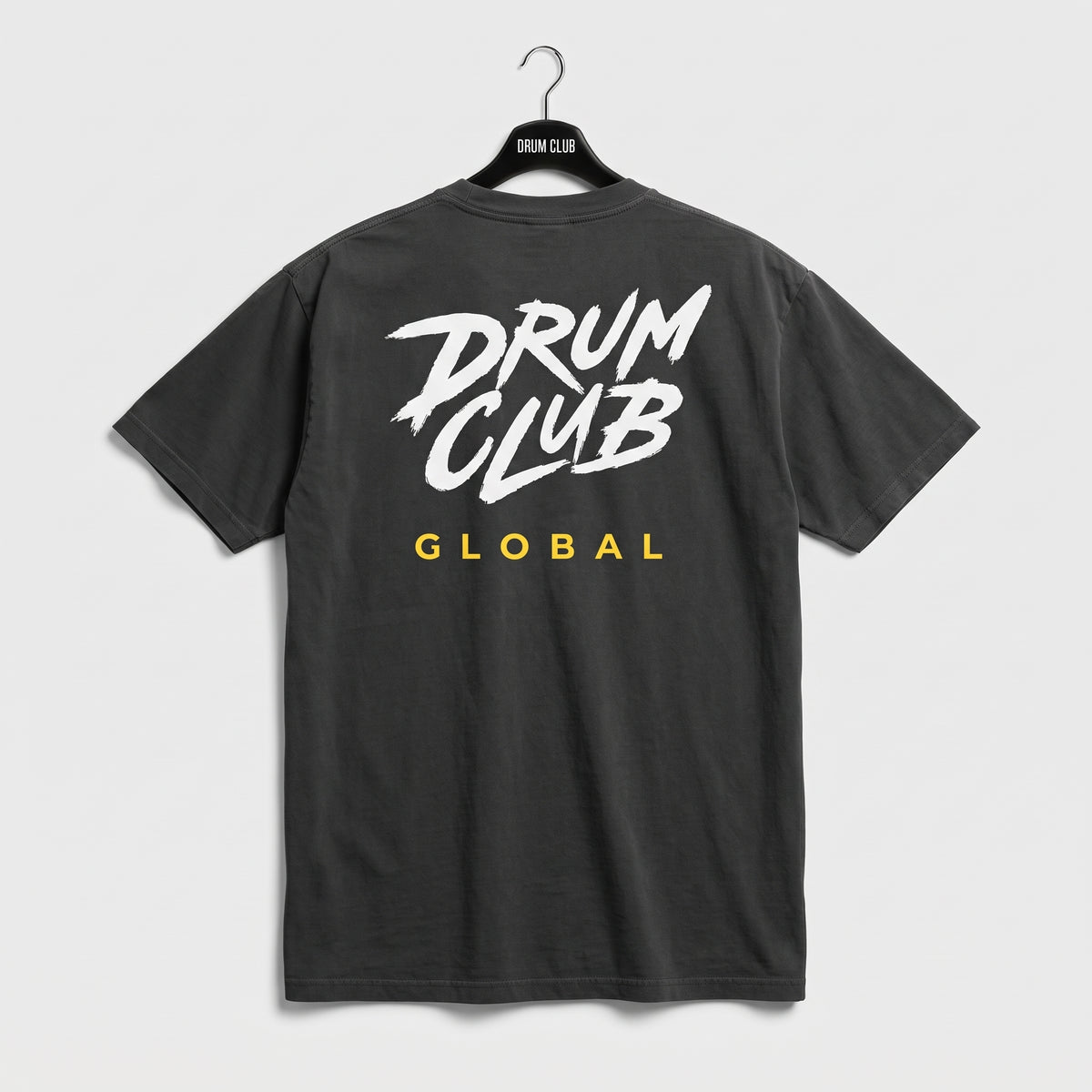 Back of charcoal Drum Club T-shirt with a large white logo and yellow Global lettering.